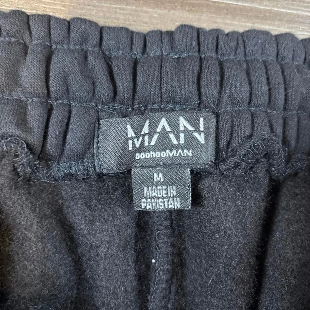 BoohooMAN black shorts with white side panels and red 'HOMME' text, size M